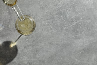 Photo of Pouring white wine into glass at grey table, top view. Space for text