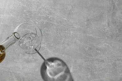 Photo of Pouring white wine into glass at grey table, top view. Space for text