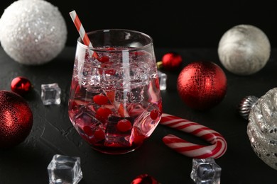 Photo of Tasty Christmas cocktail in glass, ice cubes and decor on black table, closeup