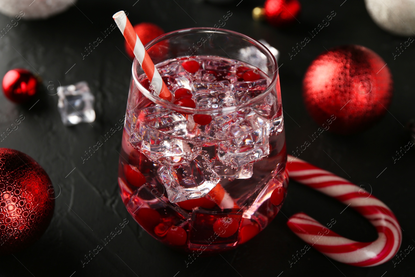 Photo of Tasty Christmas cocktail in glass and decor on black table, closeup