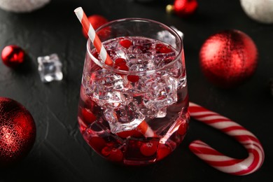 Photo of Tasty Christmas cocktail in glass and decor on black table, closeup