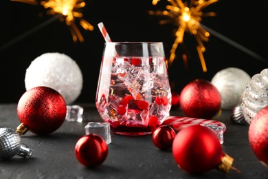 Photo of Tasty Christmas cocktail in glass and decor on black table against blurred lights, closeup