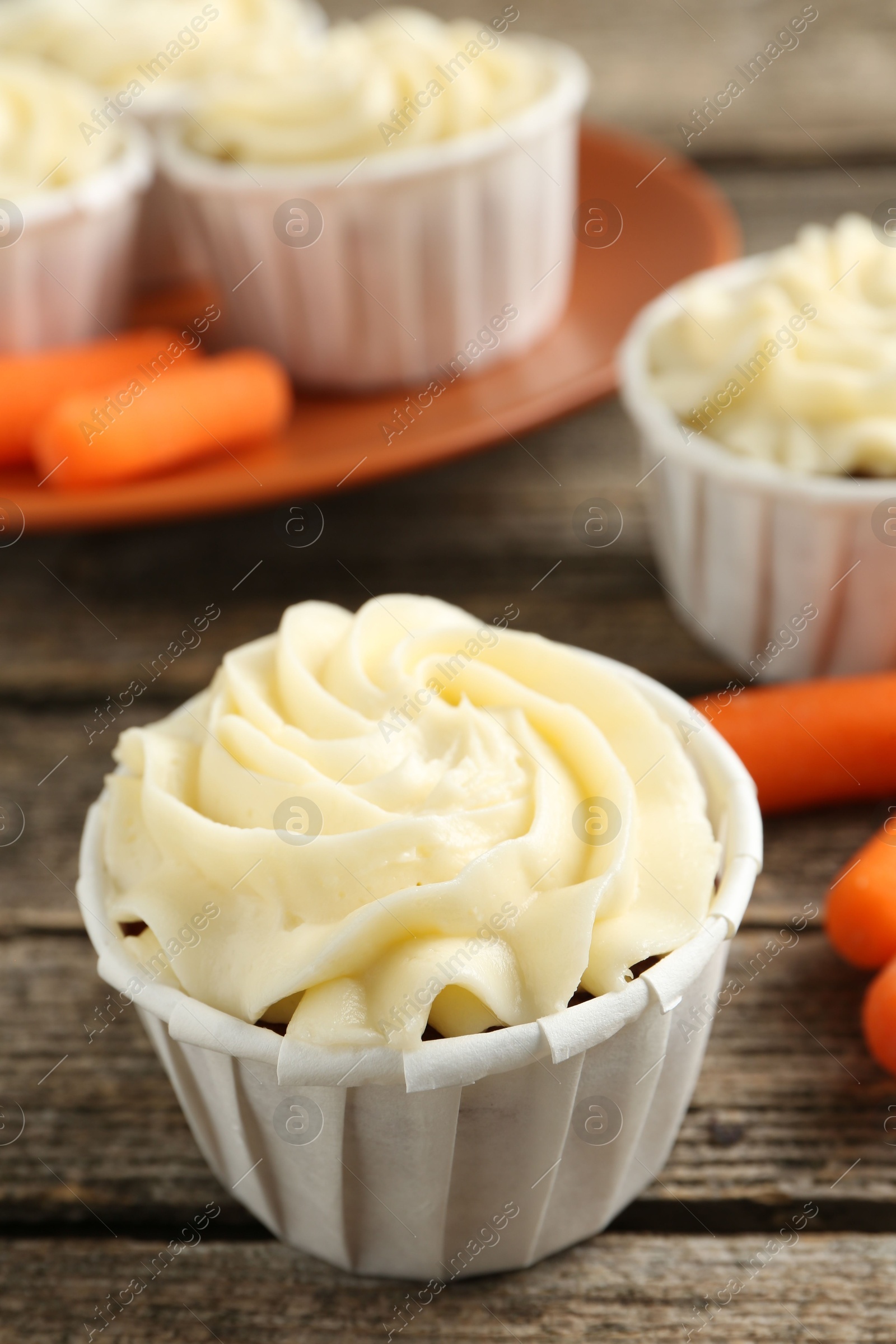 Photo of Delicious carrot muffins and fresh vegetables on wooden table, closeup