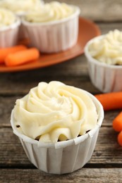 Photo of Delicious carrot muffins and fresh vegetables on wooden table, closeup