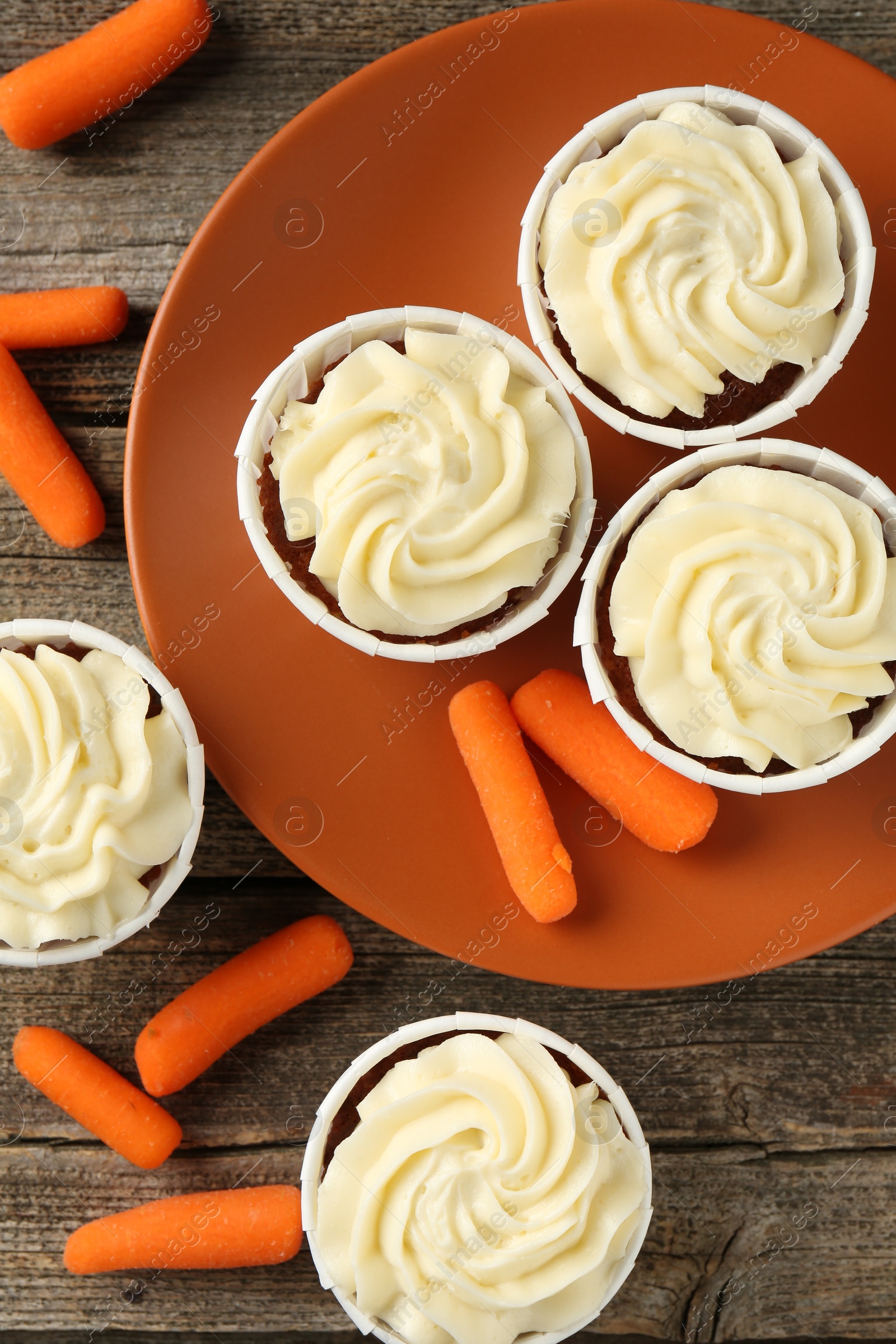 Photo of Tasty carrot muffins and fresh vegetables on wooden table, flat lay