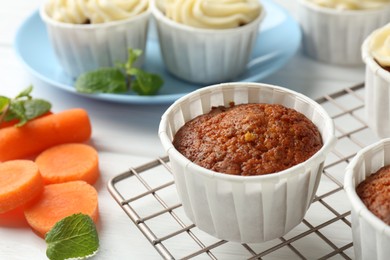 Photo of Delicious carrot muffins and fresh vegetable on white wooden table, closeup