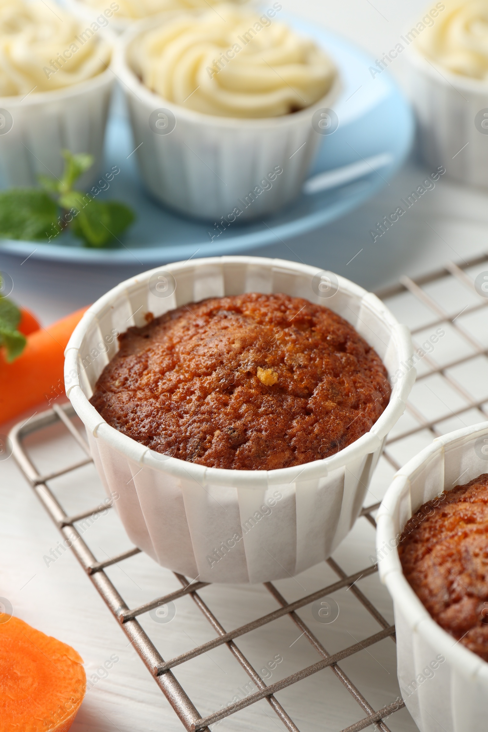 Photo of Delicious carrot muffins and fresh vegetable on white wooden table, closeup