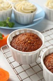 Photo of Delicious carrot muffins and fresh vegetable on white wooden table, closeup