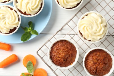 Photo of Delicious carrot muffins with fresh vegetables and mint on white wooden table, flat lay