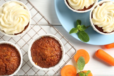 Photo of Delicious carrot muffins with fresh vegetables and mint on white wooden table, flat lay