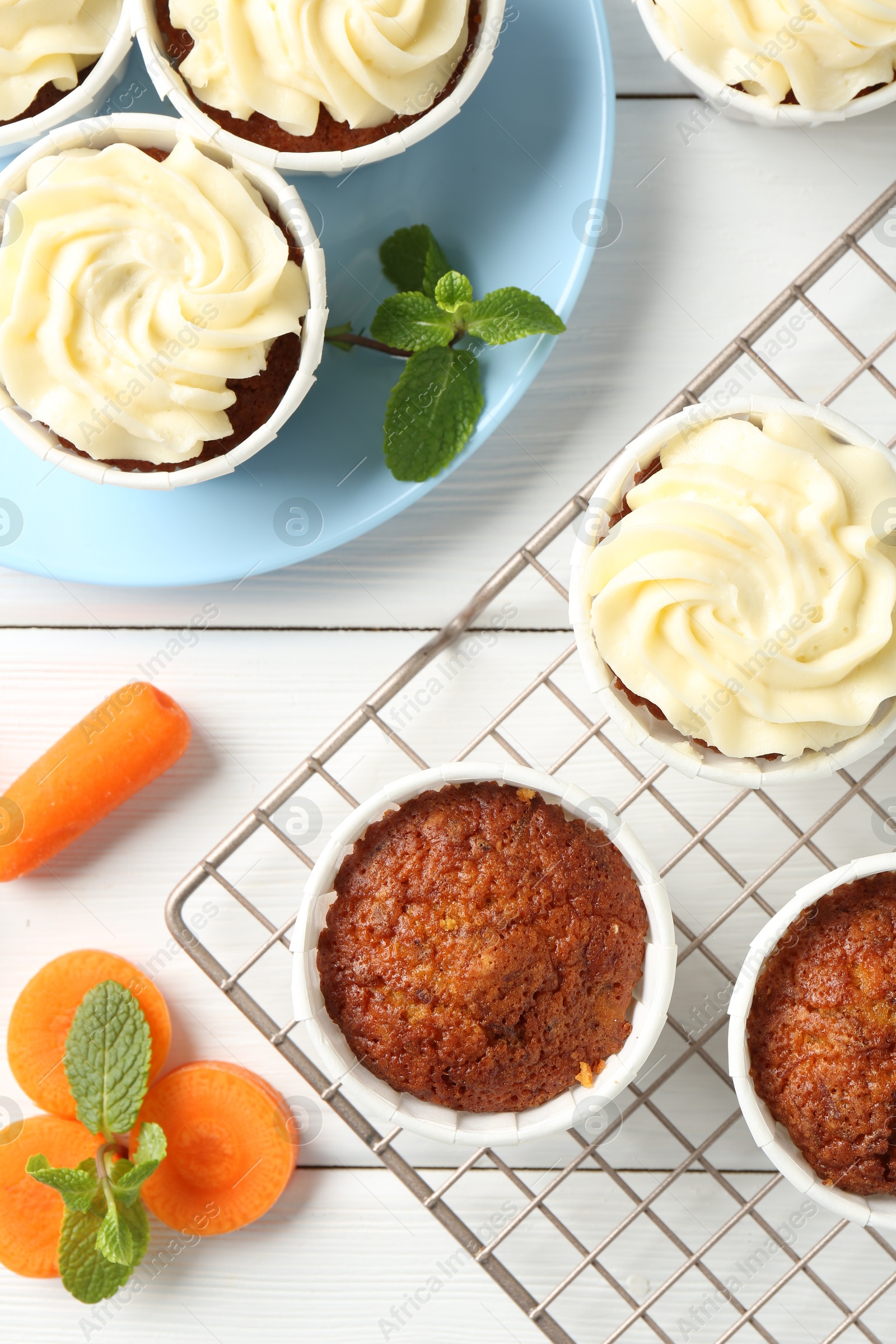 Photo of Delicious carrot muffins with fresh vegetables and mint on white wooden table, flat lay