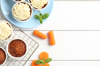 Photo of Tasty carrot muffins with fresh vegetables and mint on white wooden table, flat lay. Space for text