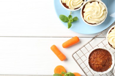 Photo of Tasty carrot muffins with fresh vegetables and mint on white wooden table, flat lay. Space for text