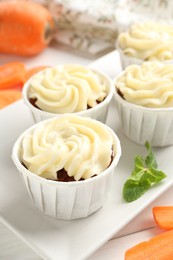 Photo of Tasty carrot muffins and fresh vegetable on white table, closeup