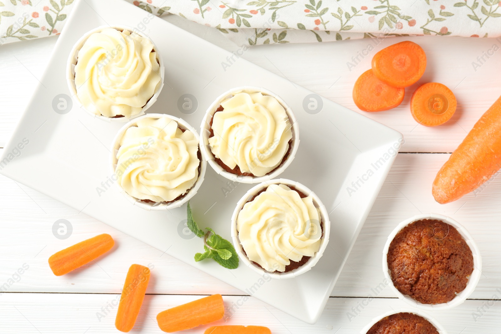 Photo of Delicious carrot muffins with fresh vegetables and mint on white wooden table, flat lay