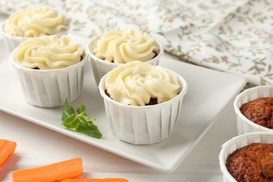 Photo of Delicious carrot muffins and fresh vegetable on white wooden table, closeup