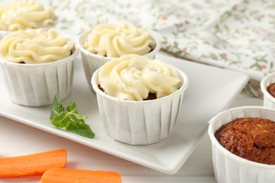 Photo of Delicious carrot muffins and fresh vegetable on white wooden table, closeup