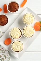 Photo of Tasty carrot muffins with fresh vegetables on white wooden table, flat lay