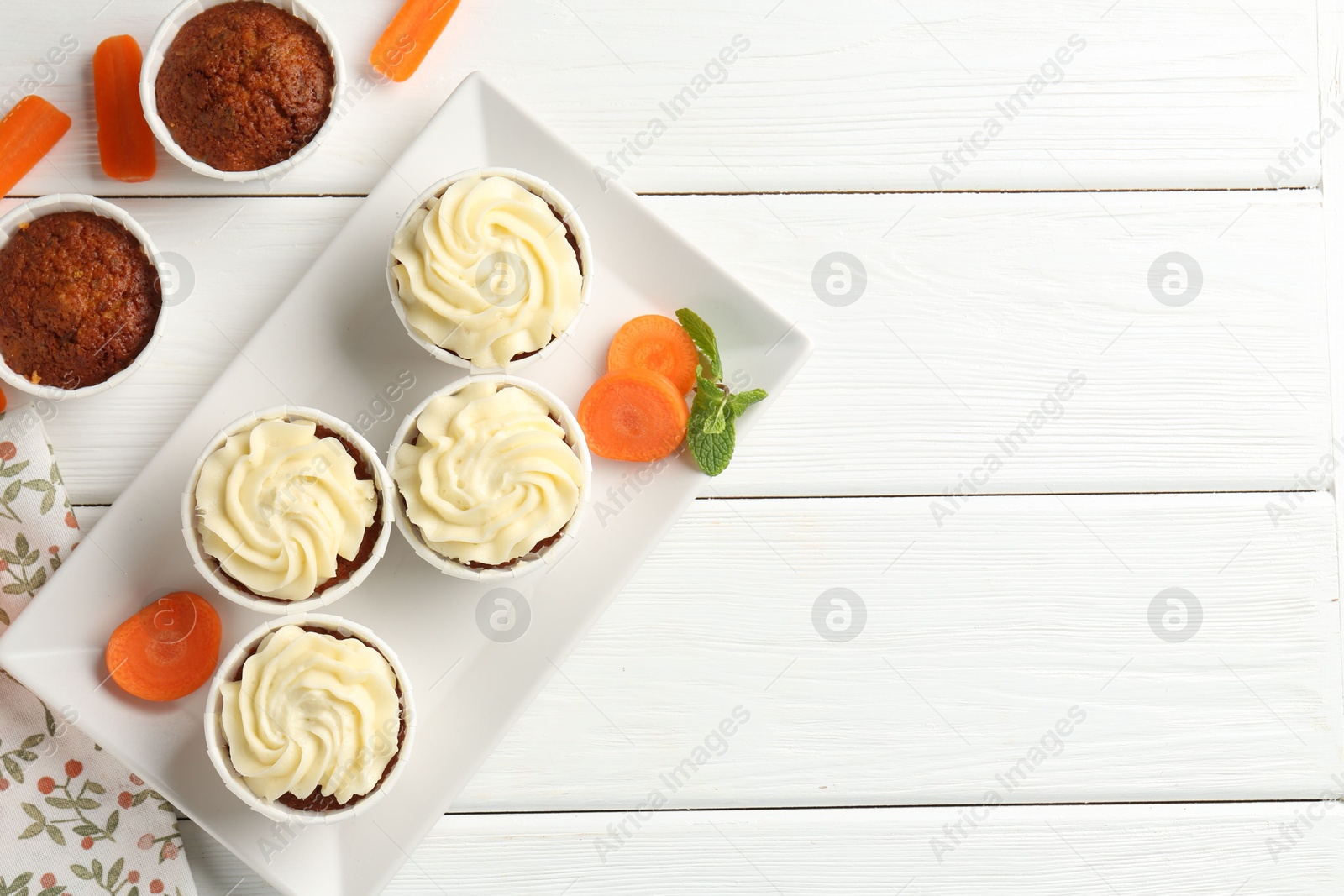 Photo of Tasty carrot muffins with fresh vegetables and mint on white wooden table, flat lay. Space for text