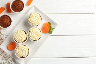 Photo of Tasty carrot muffins with fresh vegetables and mint on white wooden table, flat lay. Space for text