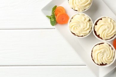 Photo of Tasty carrot muffins with fresh vegetable and mint on white wooden table, flat lay. Space for text