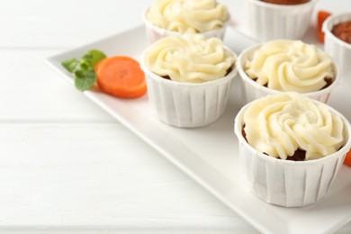 Photo of Tasty carrot muffins and fresh vegetable on white wooden table, closeup. Space for text