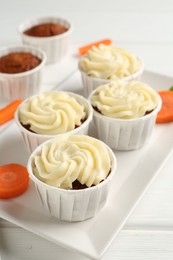 Photo of Delicious carrot muffins and fresh vegetable on white wooden table, closeup