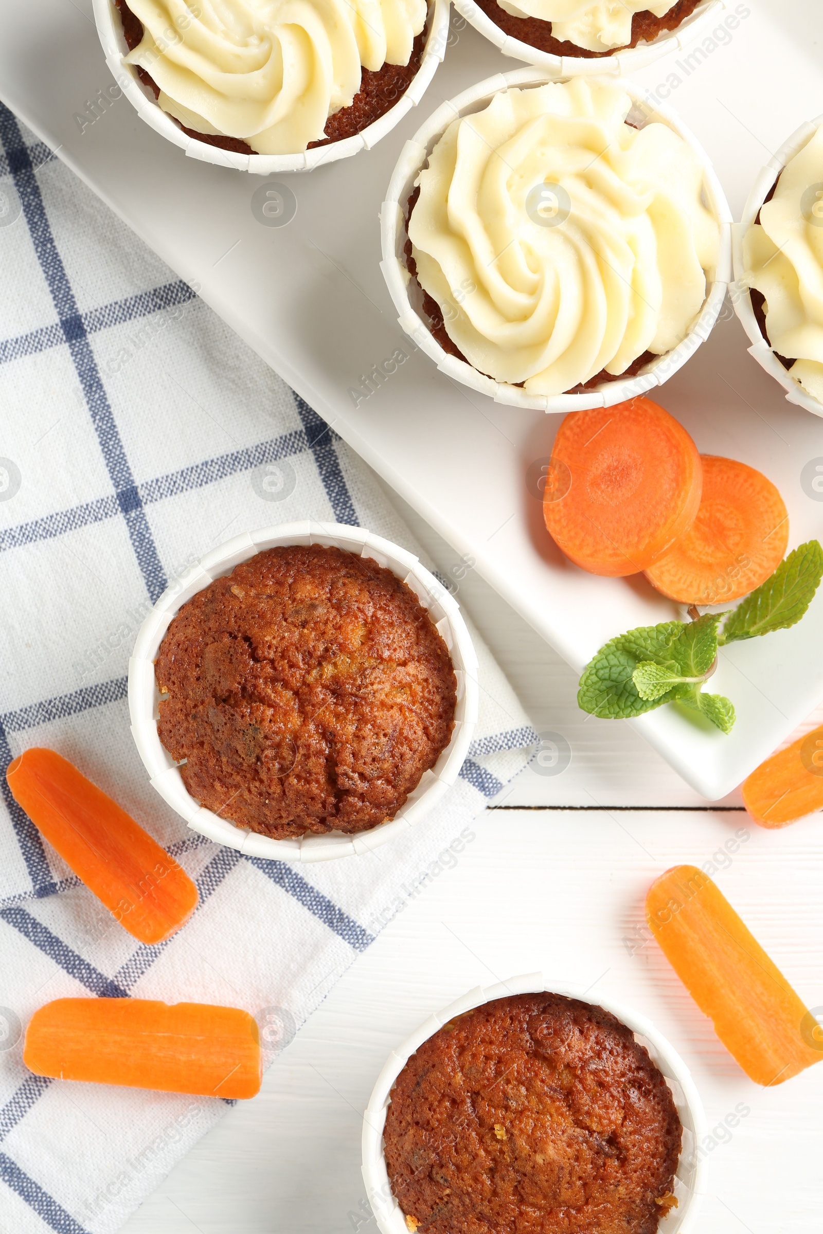 Photo of Delicious carrot muffins with fresh vegetables and mint on white wooden table, flat lay