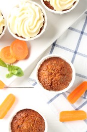 Photo of Delicious carrot muffins with fresh vegetables and mint on white wooden table, flat lay