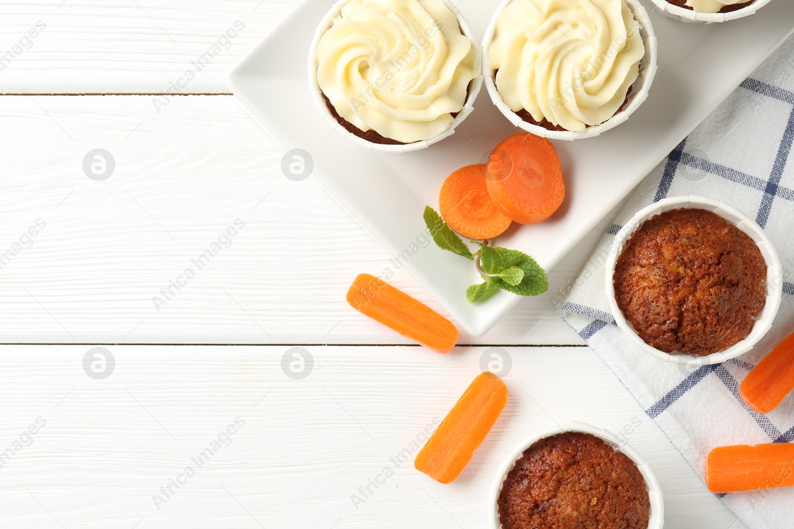 Photo of Tasty carrot muffins with fresh vegetables and mint on white wooden table, flat lay. Space for text