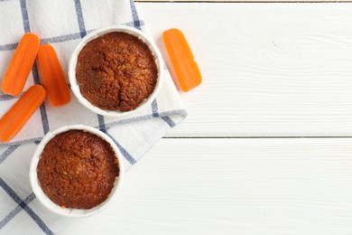 Photo of Tasty carrot muffins with fresh vegetables on white wooden table, flat lay. Space for text