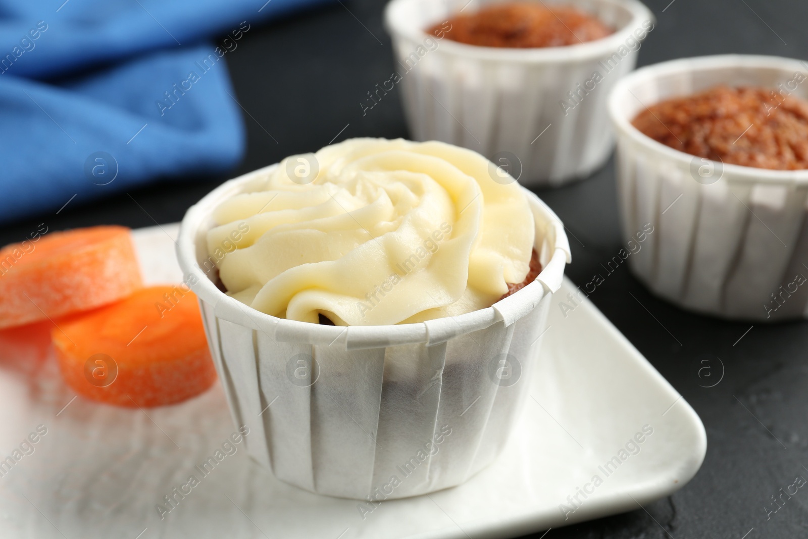 Photo of Delicious carrot muffins with fresh vegetable on grey table, closeup