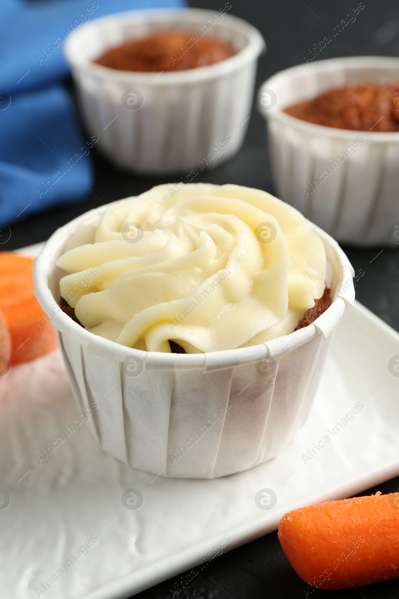 Photo of Delicious carrot muffins with fresh vegetable on grey table, closeup