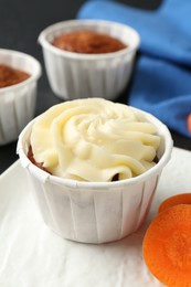 Photo of Delicious carrot muffins with fresh vegetable on grey table, closeup