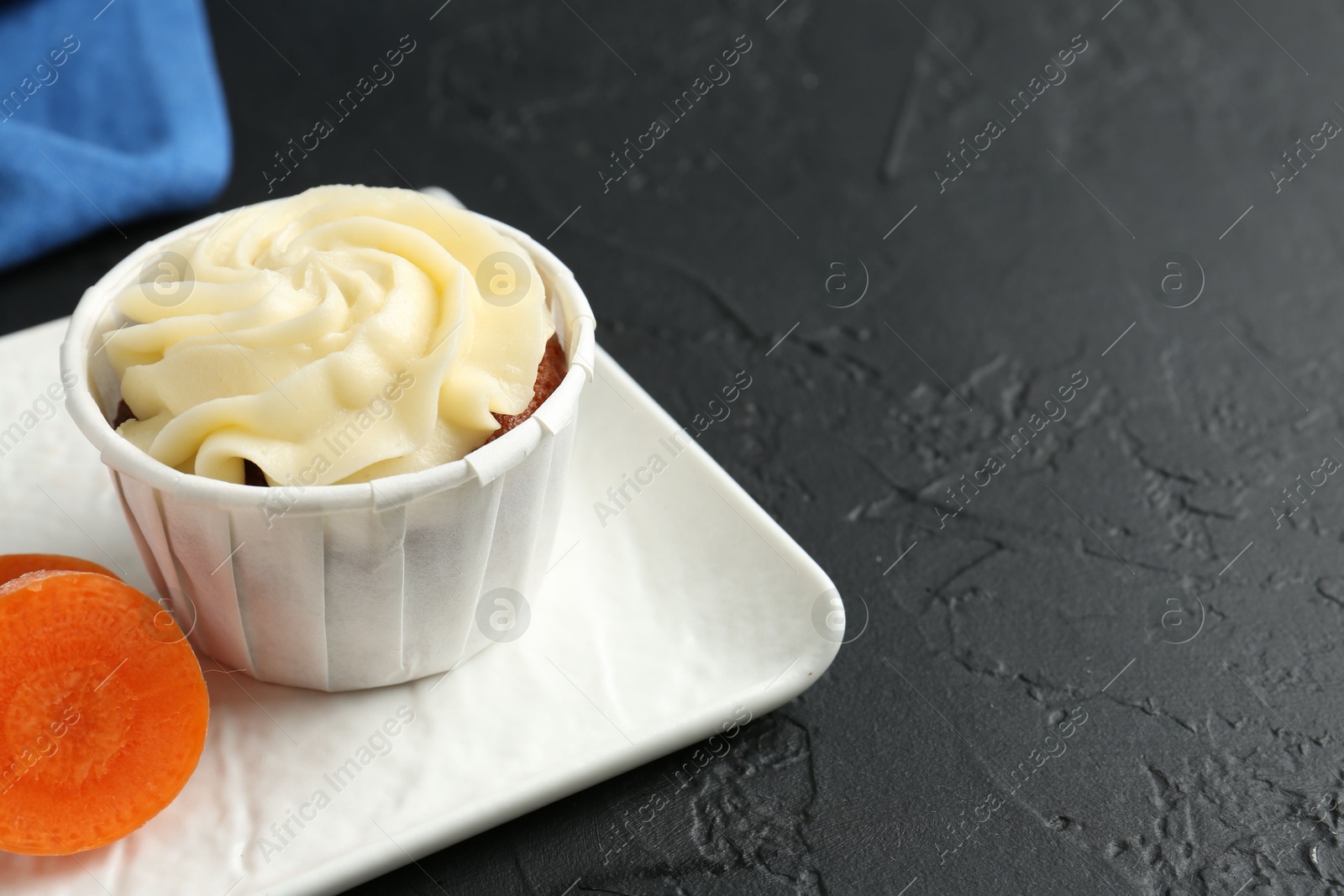 Photo of Tasty carrot muffin with fresh vegetable on grey table, closeup. Space for text