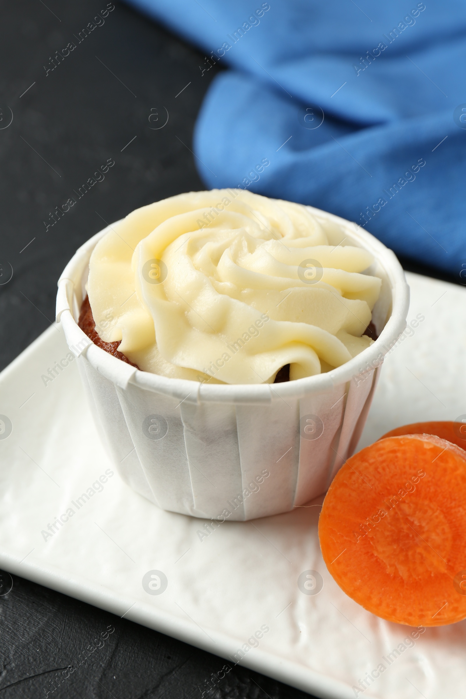 Photo of Tasty carrot muffin with fresh vegetable on grey table, closeup