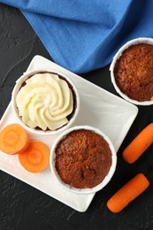 Photo of Tasty carrot muffins with fresh vegetables on grey table, flat lay