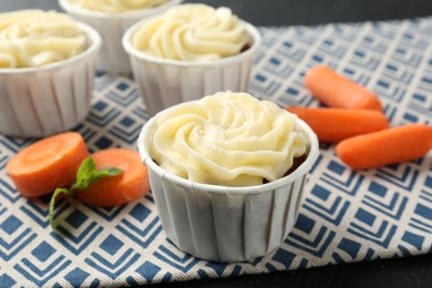 Photo of Delicious carrot muffins with fresh vegetables on black table, closeup