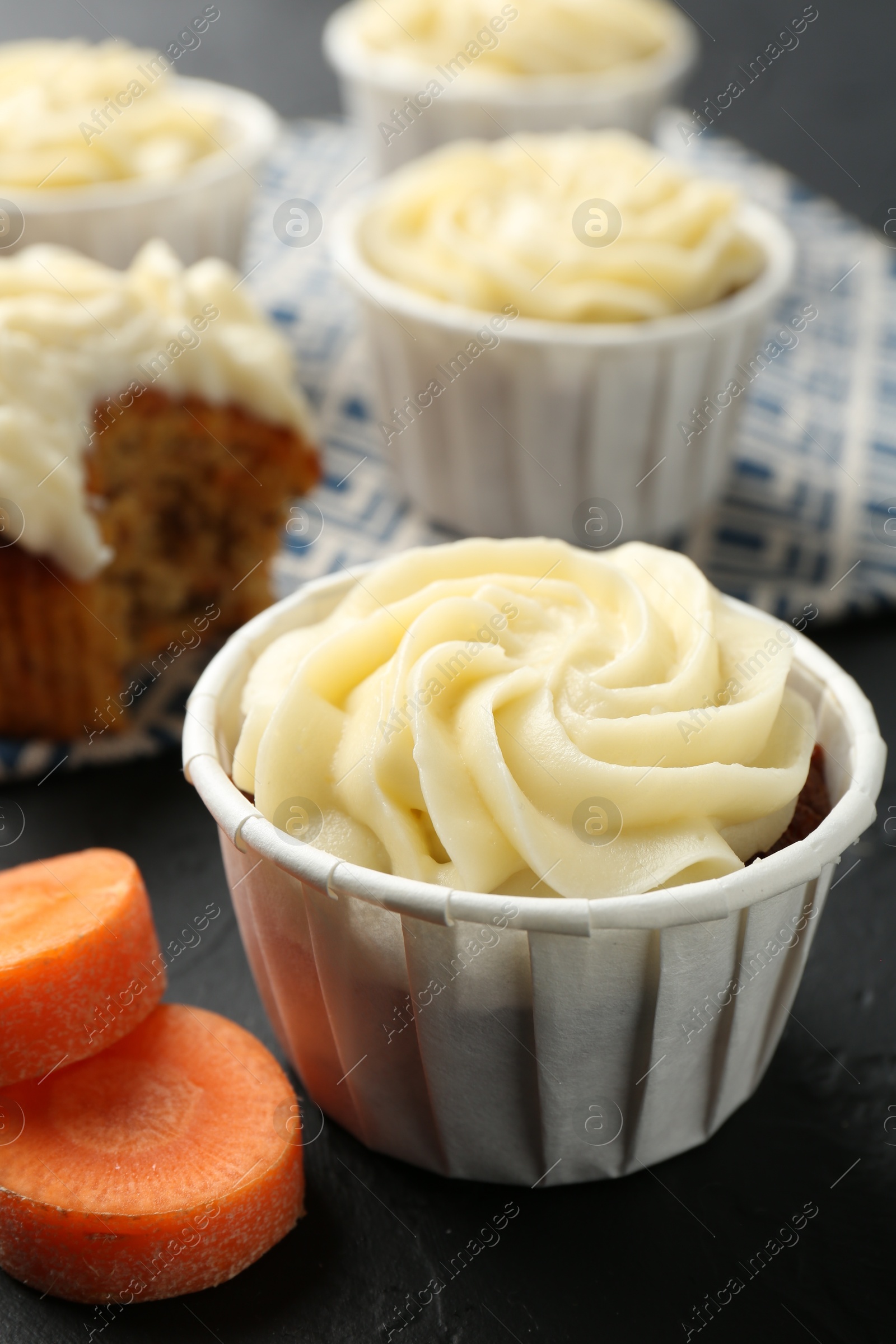 Photo of Tasty carrot muffins with fresh vegetable on black table, closeup