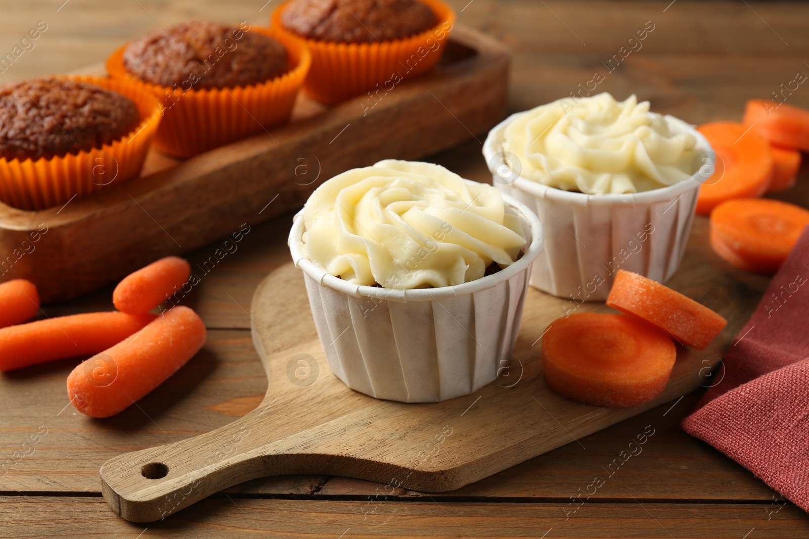 Photo of Tasty carrot muffins with fresh vegetables on wooden table, closeup