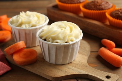 Photo of Tasty carrot muffins with fresh vegetables on wooden table, closeup