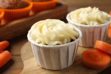 Photo of Tasty carrot muffins with fresh vegetables on wooden table, closeup