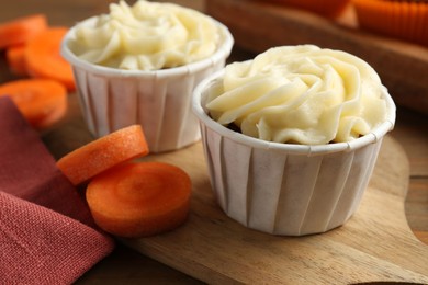 Photo of Tasty carrot muffins with fresh vegetables on wooden table, closeup