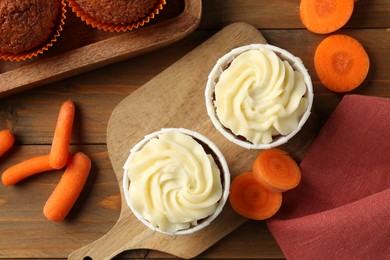 Photo of Tasty carrot muffins with fresh vegetables on wooden table, flat lay