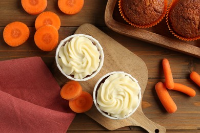 Photo of Tasty carrot muffins with fresh vegetables on wooden table, flat lay