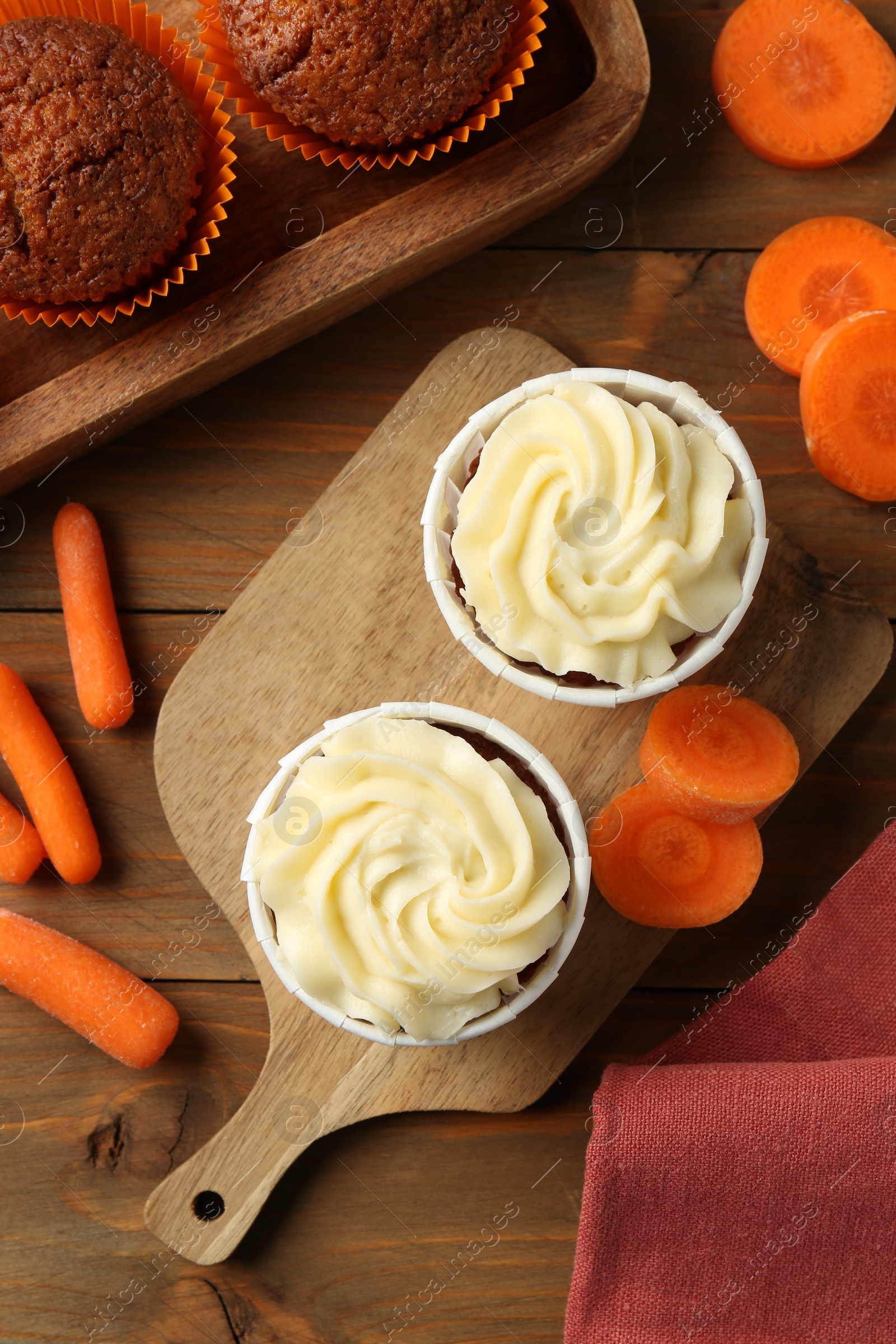 Photo of Tasty carrot muffins with fresh vegetables on wooden table, flat lay