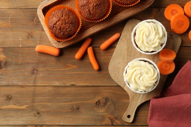 Photo of Tasty carrot muffins with fresh vegetables on wooden table, flat lay. Space for text