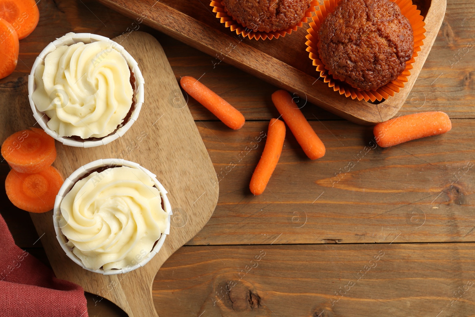 Photo of Tasty carrot muffins with fresh vegetables on wooden table, flat lay. Space for text