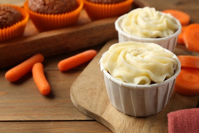 Photo of Tasty carrot muffins with fresh vegetables on wooden table, closeup. Space for text