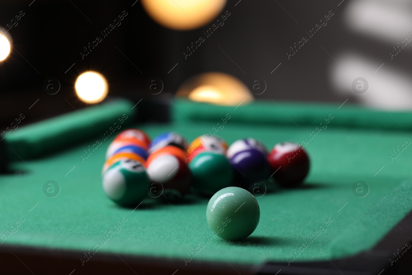 Photo of Billiard balls in triangle on green table indoors, closeup. Space for text